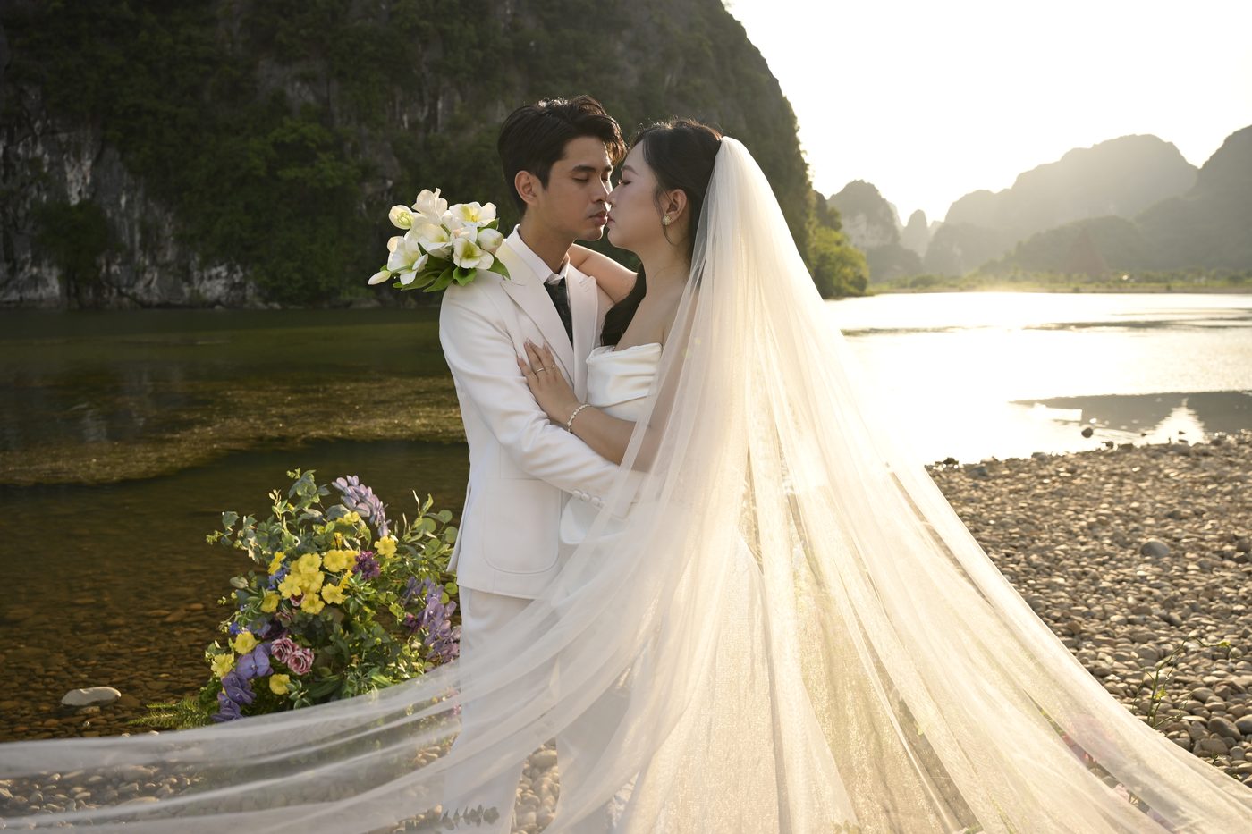 Chú rể ôm cô dâu bên sông lúc hoàng hôn